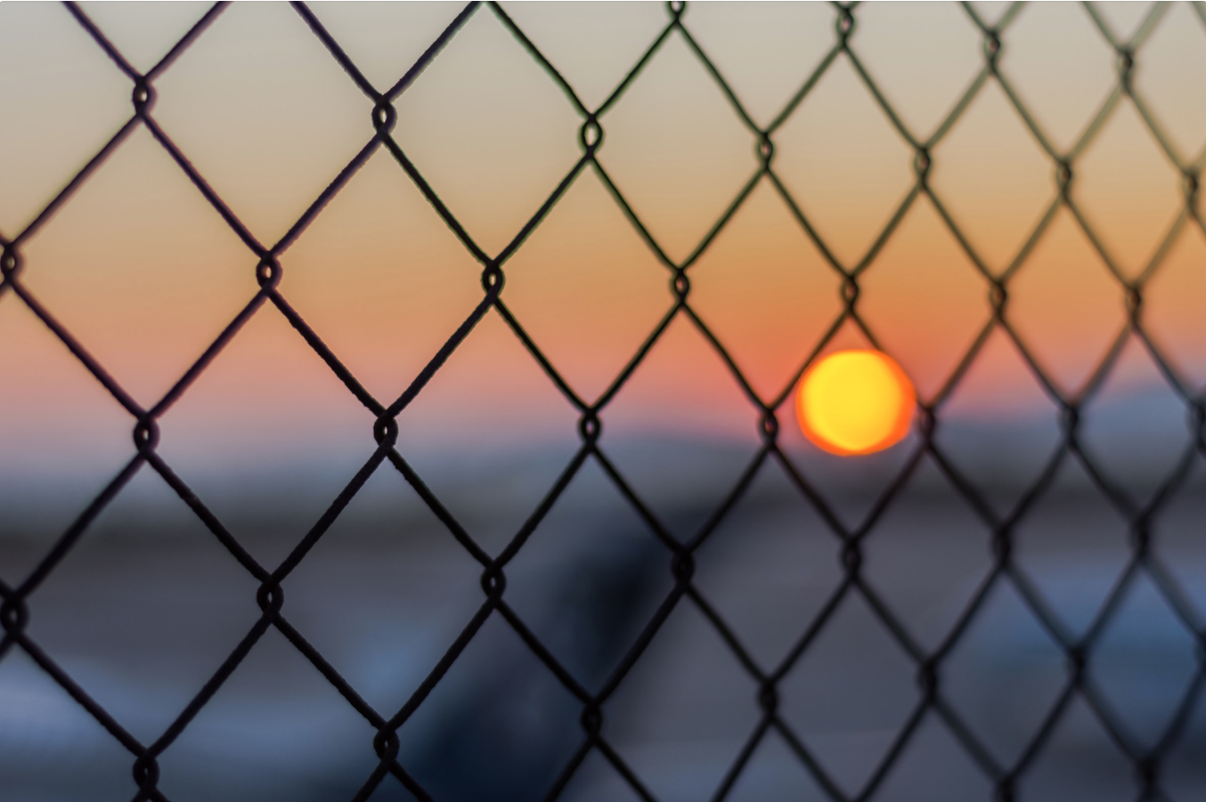 Sun behind fence